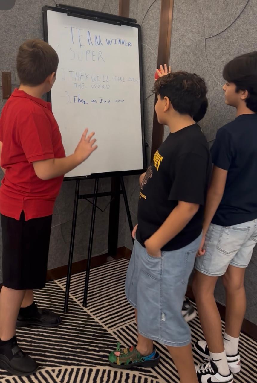 Kids presenting their team ideas on a whiteboard at Transformation Avenue Dubai